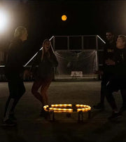 Four Spikeball players using the Spikebrite Kit in a dark court
