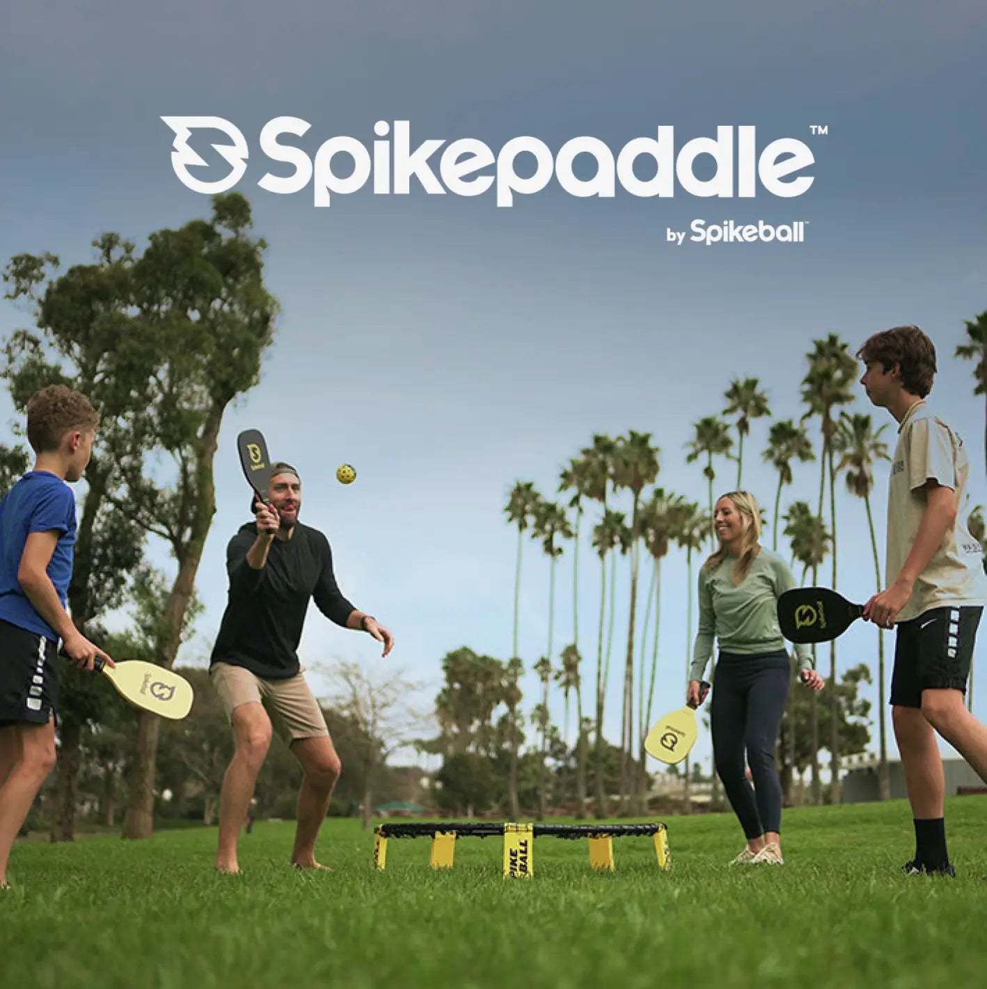 Family playing SpikePaddle by Spikeball on the yard