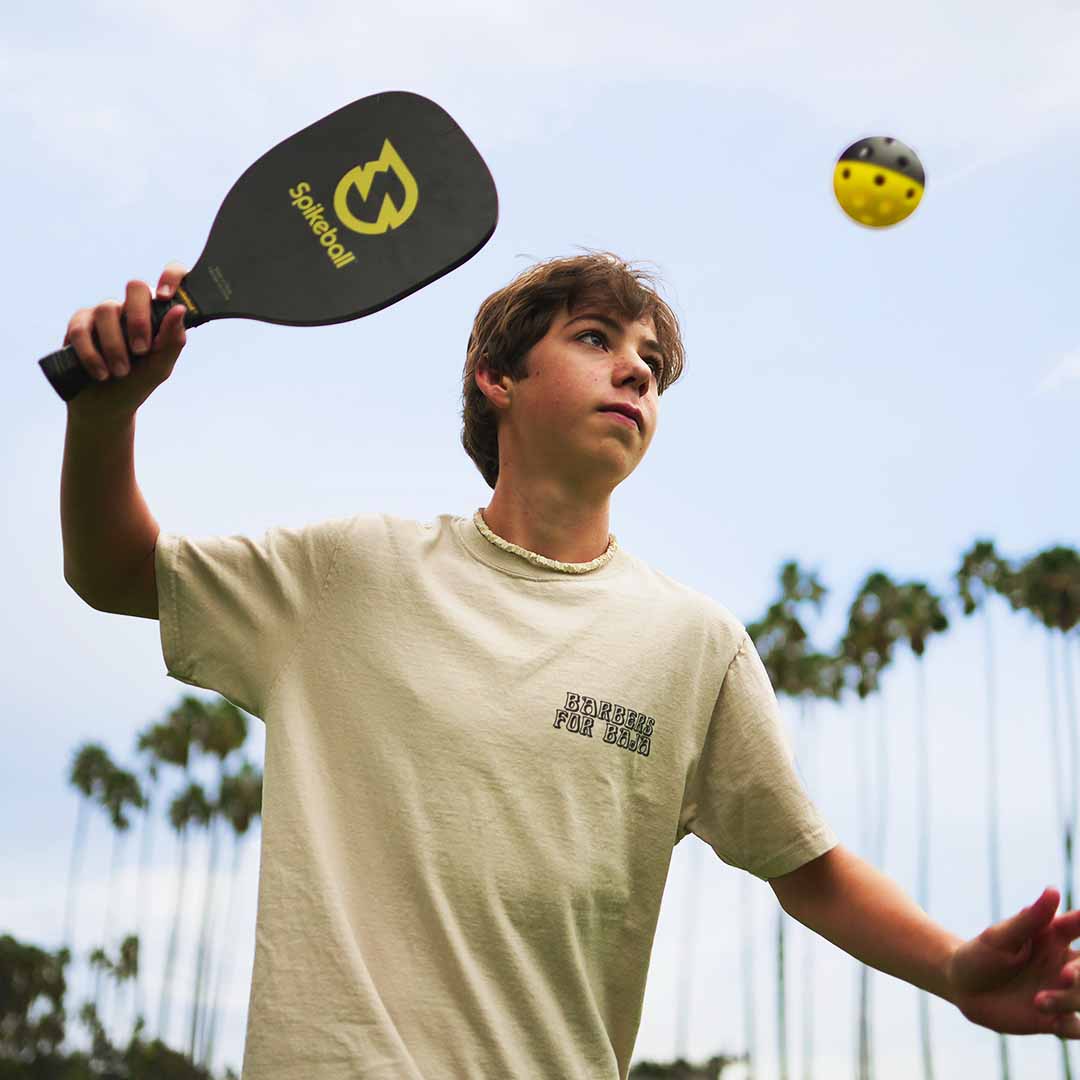Young man playing Spikeball with black SpikePaddles