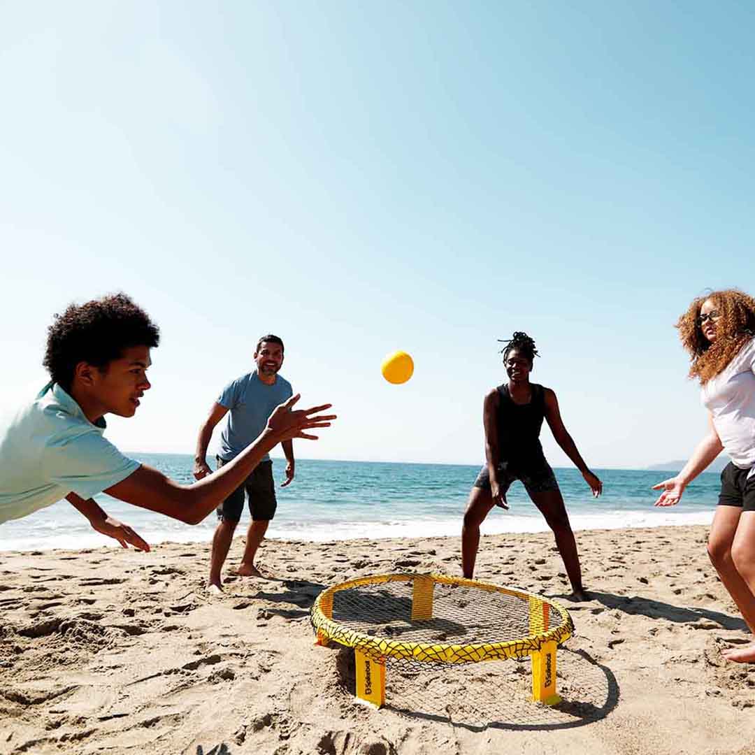 Group of friends playing Spikeball at the beach